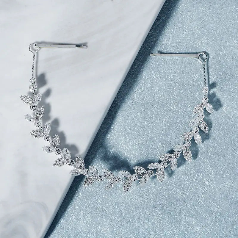 Silver leaf-shaped bridal headband adorned with sparkling crystals and delicate metal clasps for wedding hair accessory.
