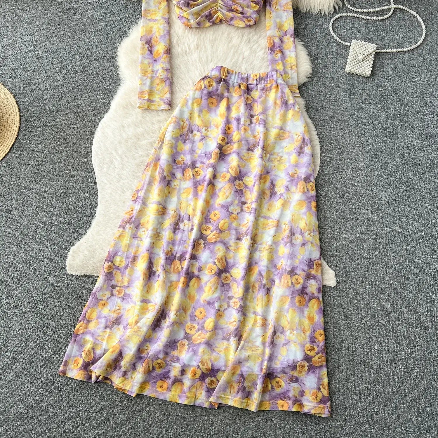 a flowing long-sleeved maxi dress in vibrant yellow and purple floral pattern with an elastic waistband paired with a two piece mesh skirt set featuring a marble print and elastic closure type