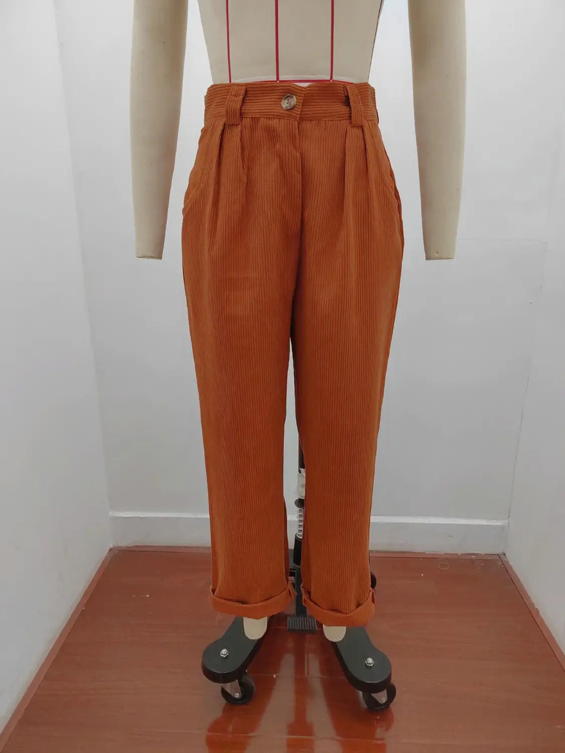 Pantalon en velours côtelé taille haute ample en orange, fermeture par boutons et bas retroussés.