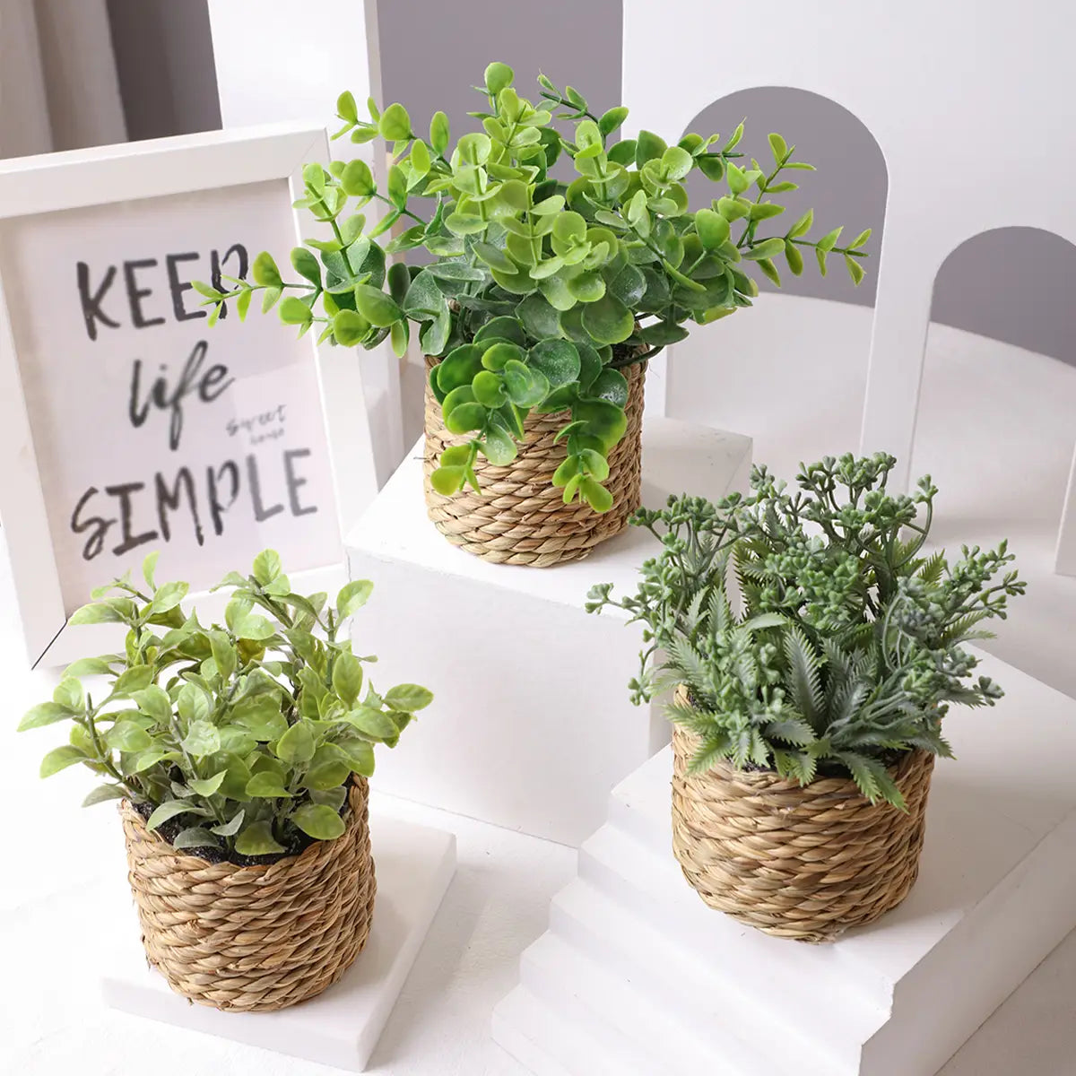 three artificial green eucalyptus flowers in small potted plants nestled in woven natural fiber baskets measuring 17cm.