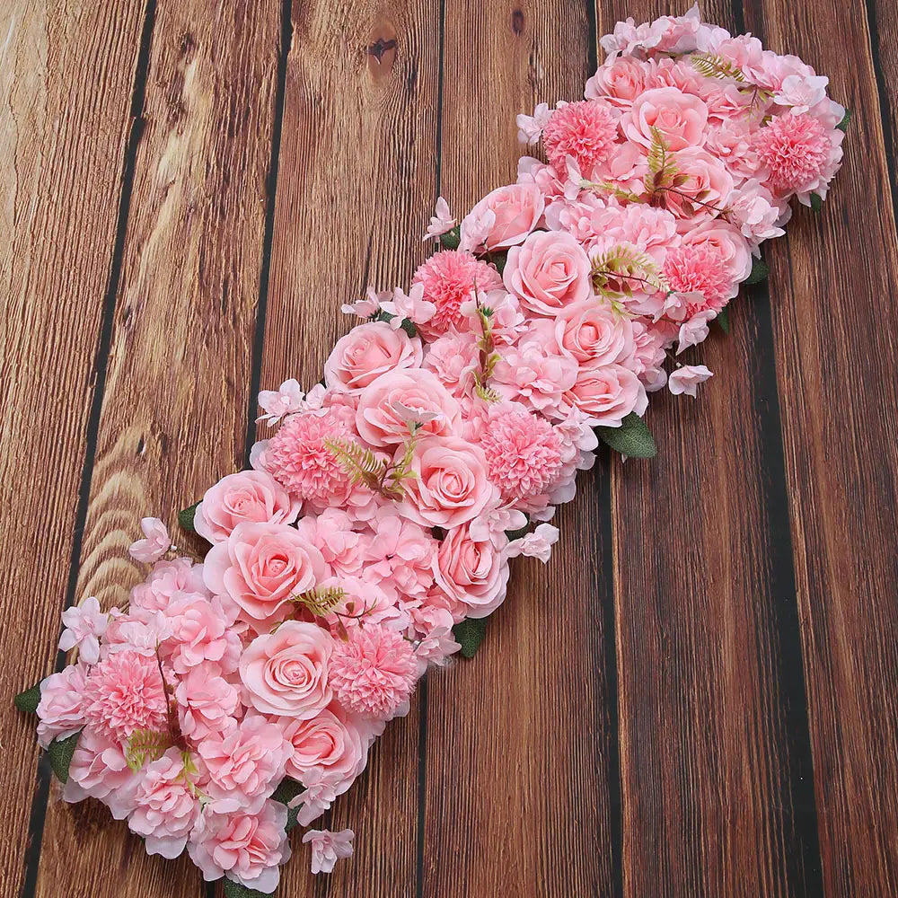 Composition de fleurs de sol pour mariage de rose blanche, présentant une délicate guirlande florale rose en tissu synthétique, avec des roses pompons et des accents de feuillage vert.