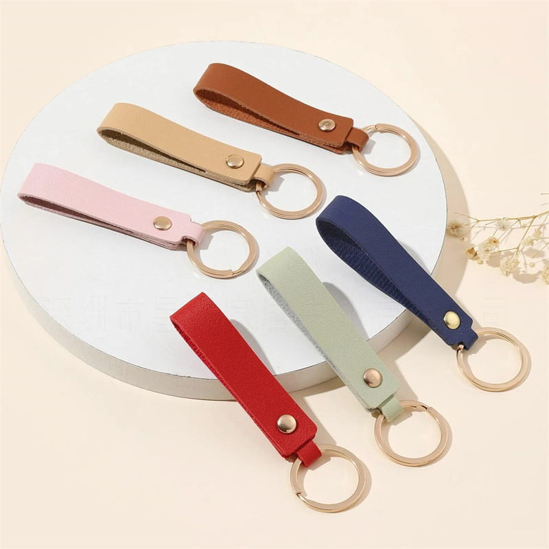 A set of six colorful pu leather keychain fashion metal keyrings in pink beige brown navy blue mint green and red featuring gold-toned metal rings and button closures.