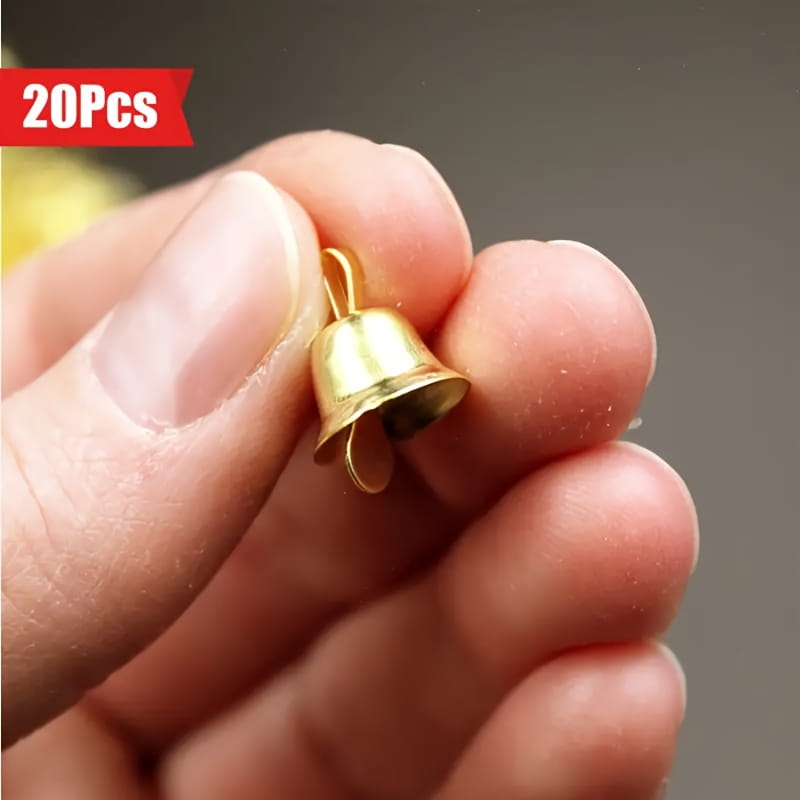 Une petite clochette de traîneau en métal doré, avec une finition métallique brillante et un sommet bouclé pour l’attache, issue d’un ensemble de 20 pièces.