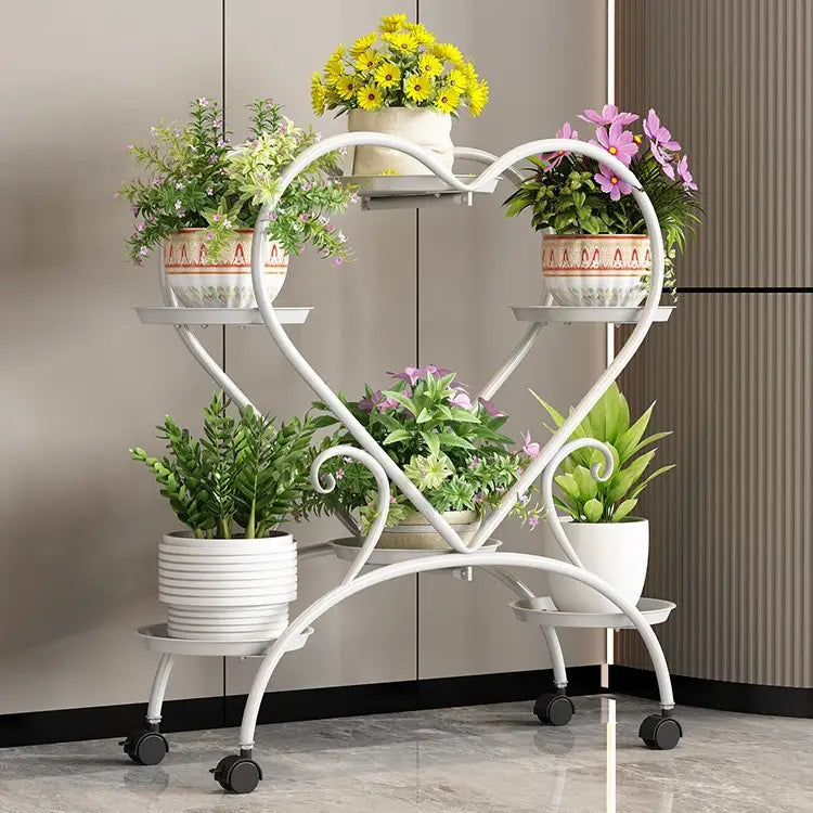 Blumenständer aus weißem Metall in Herzform mit vier Ebenen und schwarzen Rollrädern zur Präsentation von Blumentöpfen.