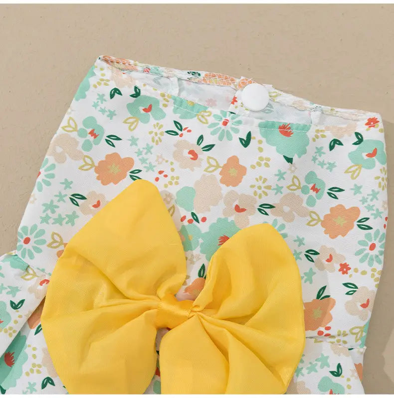 a floral dog princess dress with a bright yellow fabric bow features white floral-patterned pants adorned in the back side of the garment