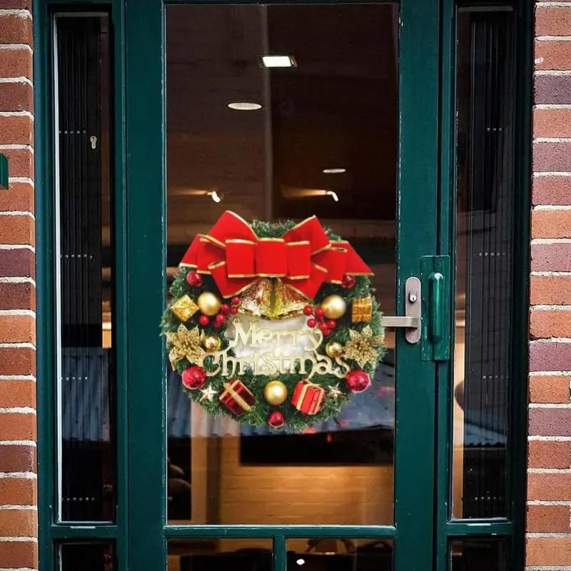 A festive red and gold christmas wreath made of velvet with a large bow decorative ornaments and merry christmas lettering designed as holiday door hanging decor.