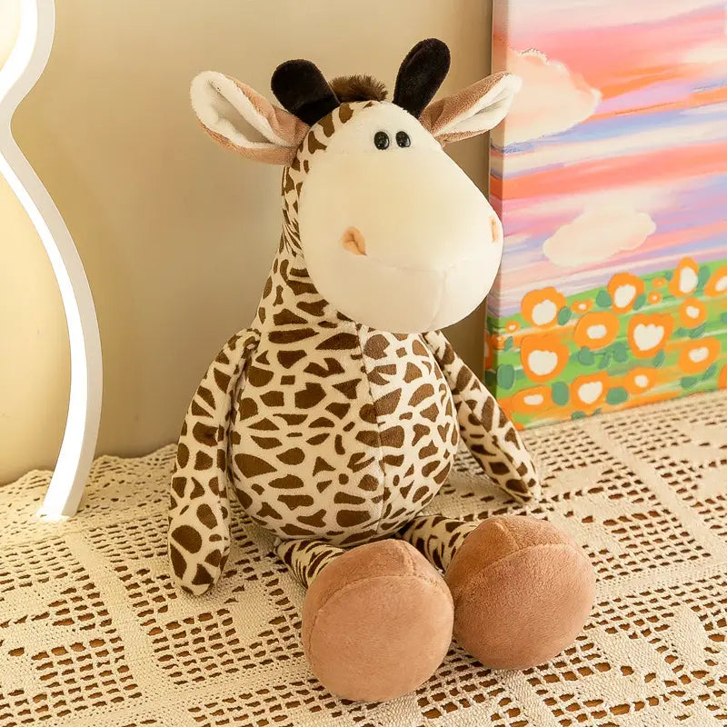 Un jouet girafe en peluche provenant de peluches d’animaux de la jungle : il présente un visage couleur crème, des taches brunes, ainsi que des oreilles et des pieds en tissu doux, confectionnés dans une matière souple.