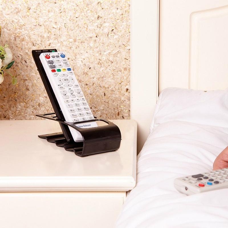black plastic remote control organizer desktop storage rack holding a white tv remote with colorful buttons