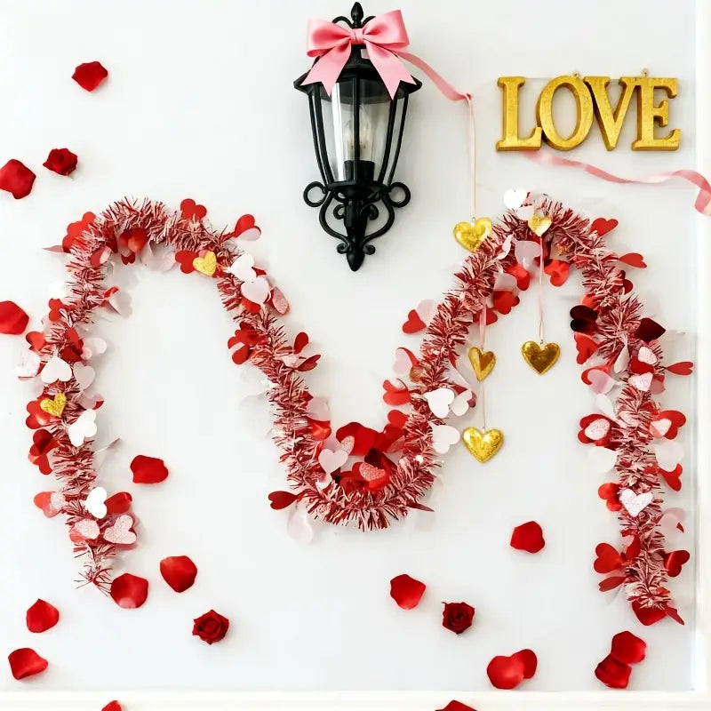 Red pink metallic heart tinsel garland featuring a shimmering red tinsel base adorned with pink white and gold paper hearts for Valentine decor.