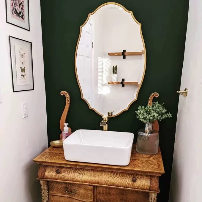 Évier à vasque rectangulaire blanc avec robinet à finition dorée sur meuble en bois, associé à une décoration murale ovale dorée ornementale de miroirs de salle de bains, mettant en valeur un style de miroir élégant pour améliorer le style des miroirs de salle de bains.