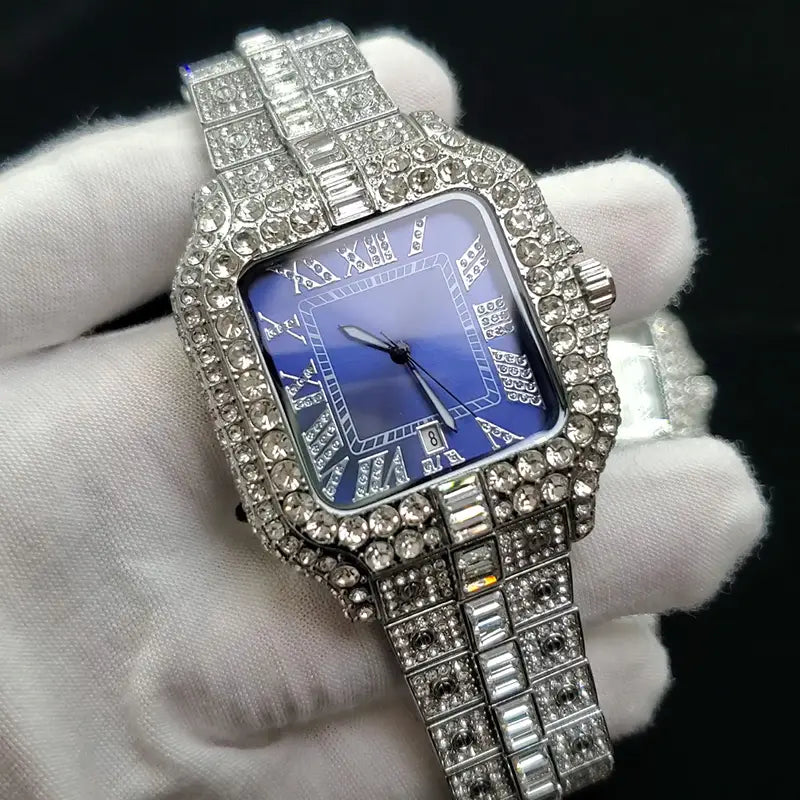 A luxurious iced out diamond square watch for men with a blue dial, roman numeral hour markers, and a diamond-encrusted stainless steel case and bracelet in silver.