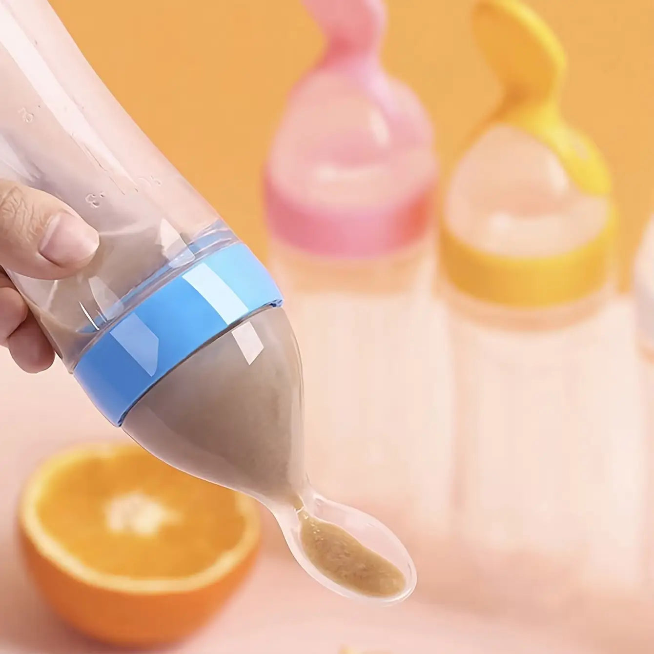 Transparentes Silikon-Babynahrungstrinkfläschchen mit blauem Band und löffelartigem Ausguss, entwickelt für eine einfache Fütterung.