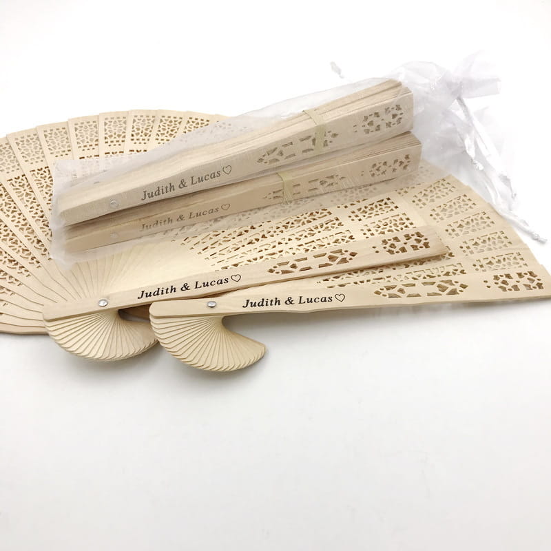 Éventails de mariage en bois beige avec des découpes fines, de style dentelle, et un texte cœur « judith et lucas » gravé, personnalisé, pour des faveurs gravées en grande quantité.