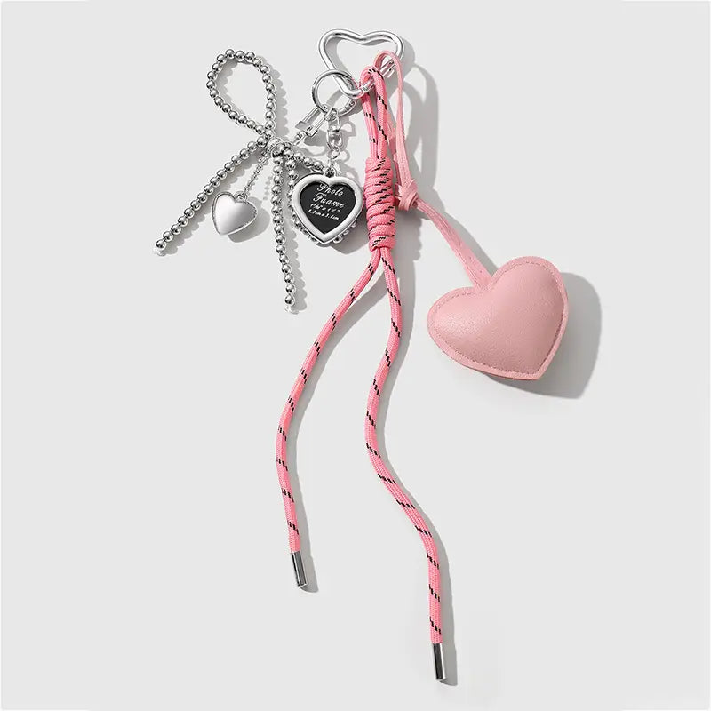Heart pendant bowknot bag keychain featuring a pink heart-shaped leather charm with a braided cord and silver-toned metal accents.
