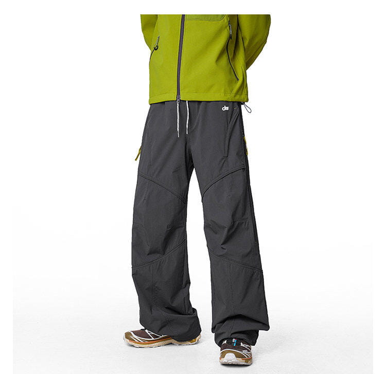 pantalones cargo impermeables de senderismo para hombre en gris oscuro, con tejido resistente, acentos de cremallera verde lima y un logotipo de marca pequeño en la cinturilla.
