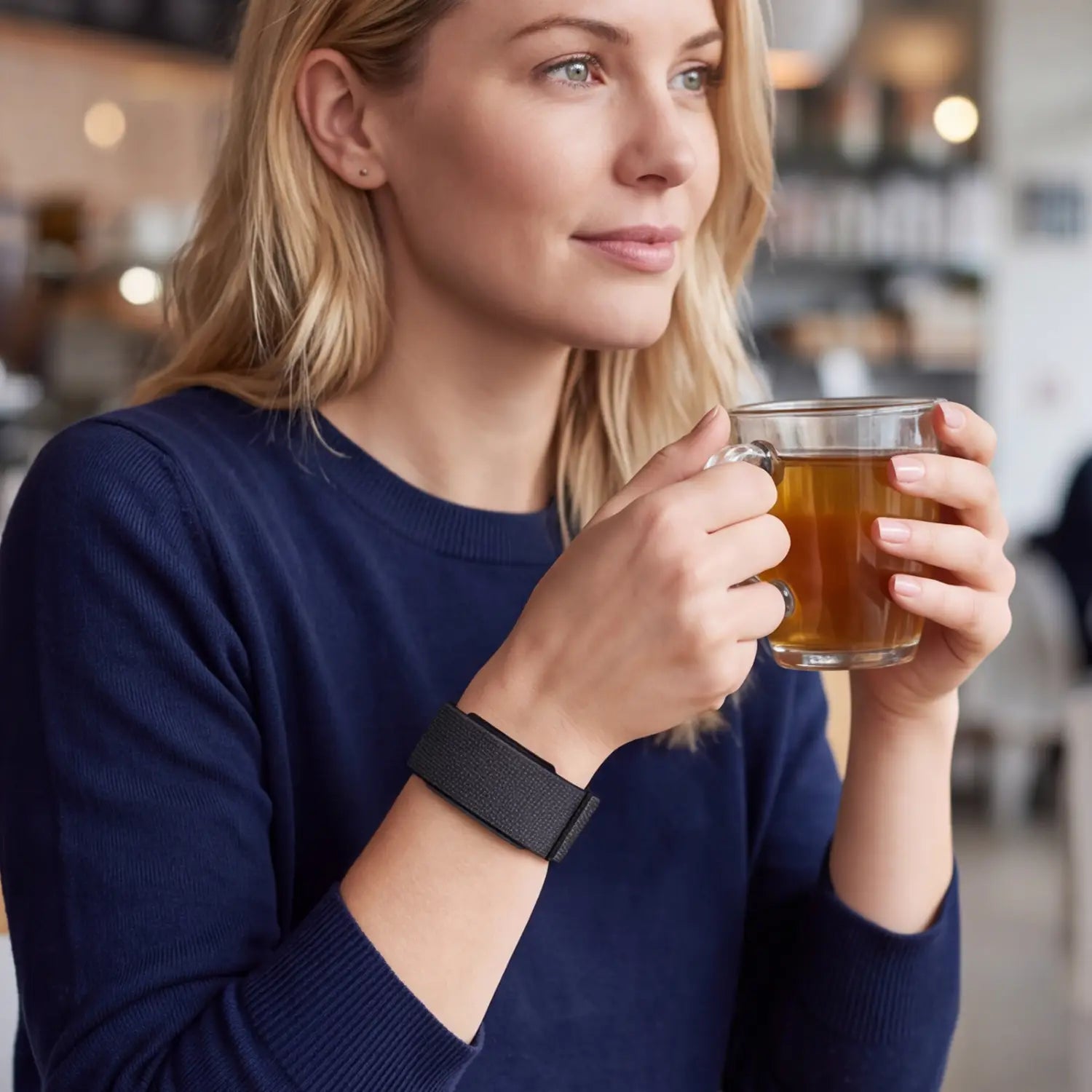 A woman holding a clear glass mug of amber tea wearing a breathable replacement strap for Cirqa smart band nylon adjustable sport watch strap.