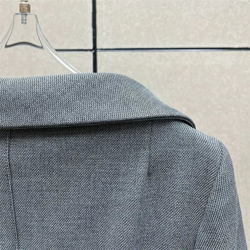 Jupe crayon grise taille haute avec un motif tissé discret, associée à une veste blazer grise texturée présentant un col structuré.