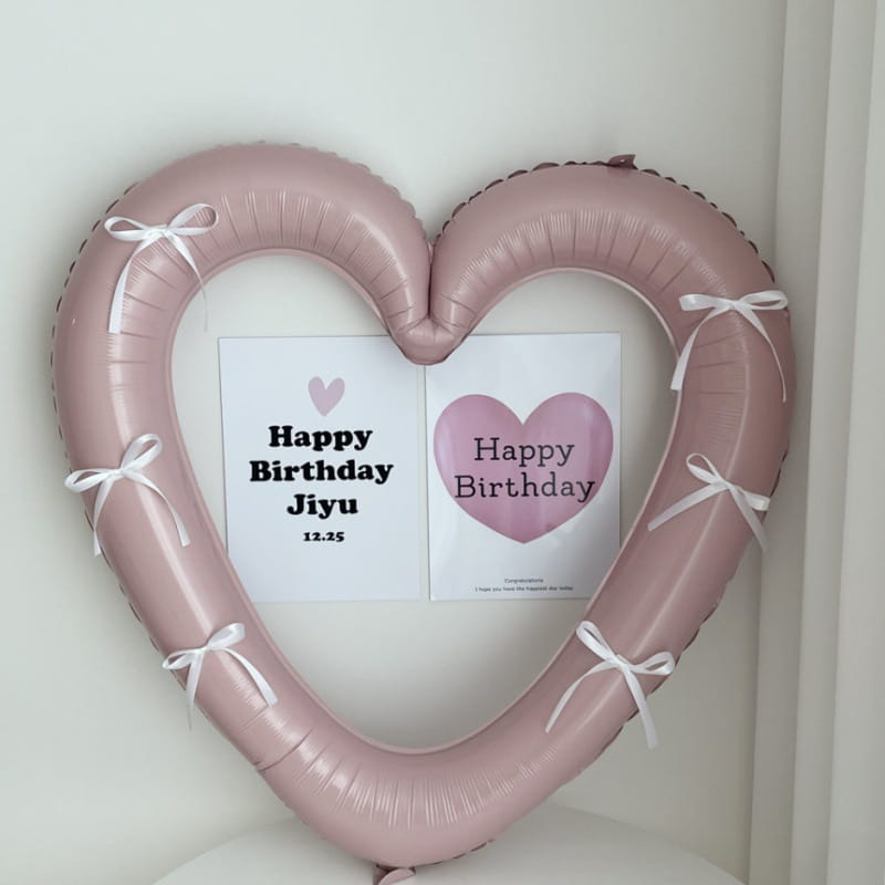 Una corona de globo de lámina para marco de foto de corazón de 40 pulgadas, rosa suave, adornada con delicadas cintas blancas.