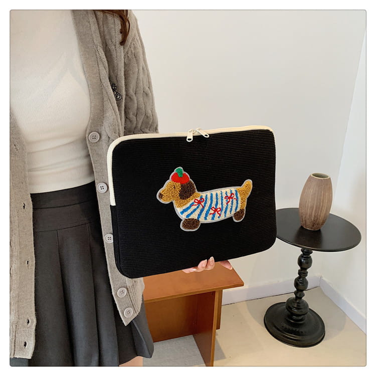 Schwarze Kord-Laptophülle für MacBook Pro mit einem farbenfrohen bestickten Dackel, der gestreifte Kleidung mit roten Schleifen und einer grünen Mütze trägt
