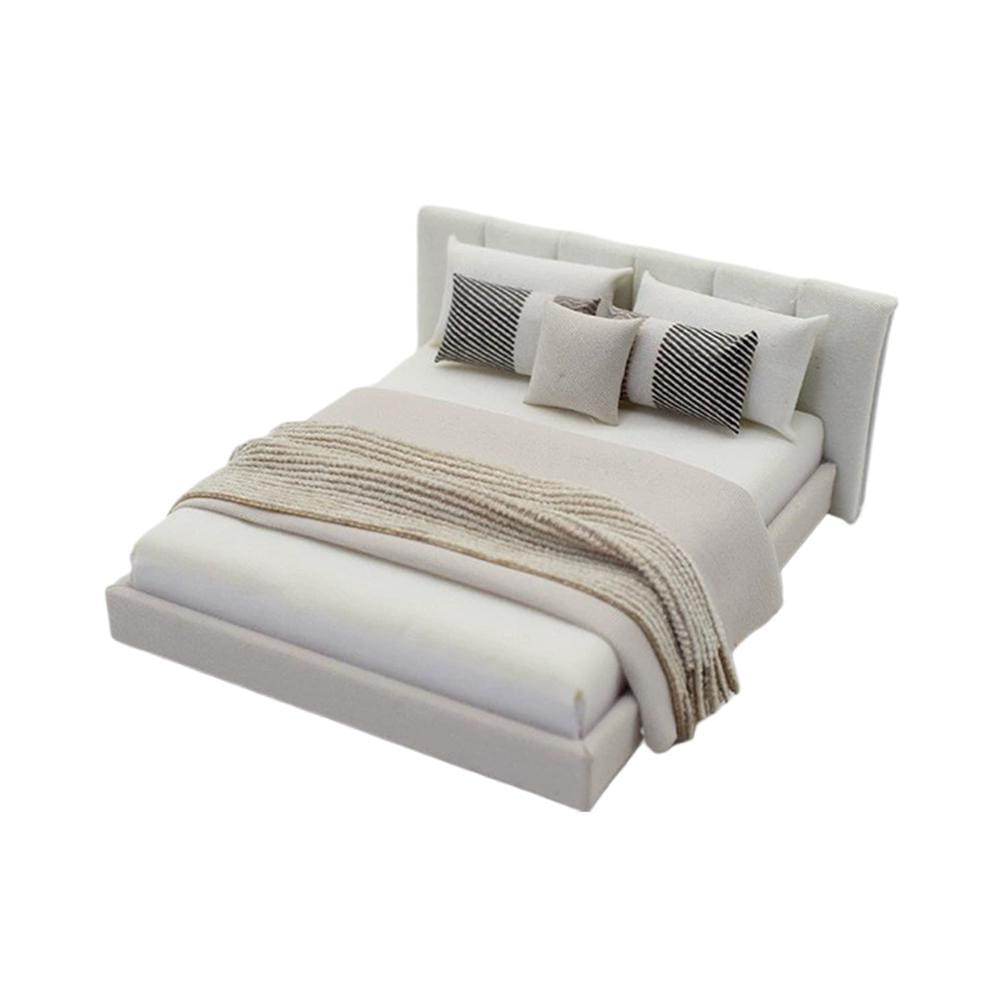 Modern miniature dollhouse double bed with cream upholstered tufted headboard and platform base dressed in neutral-toned bedding.