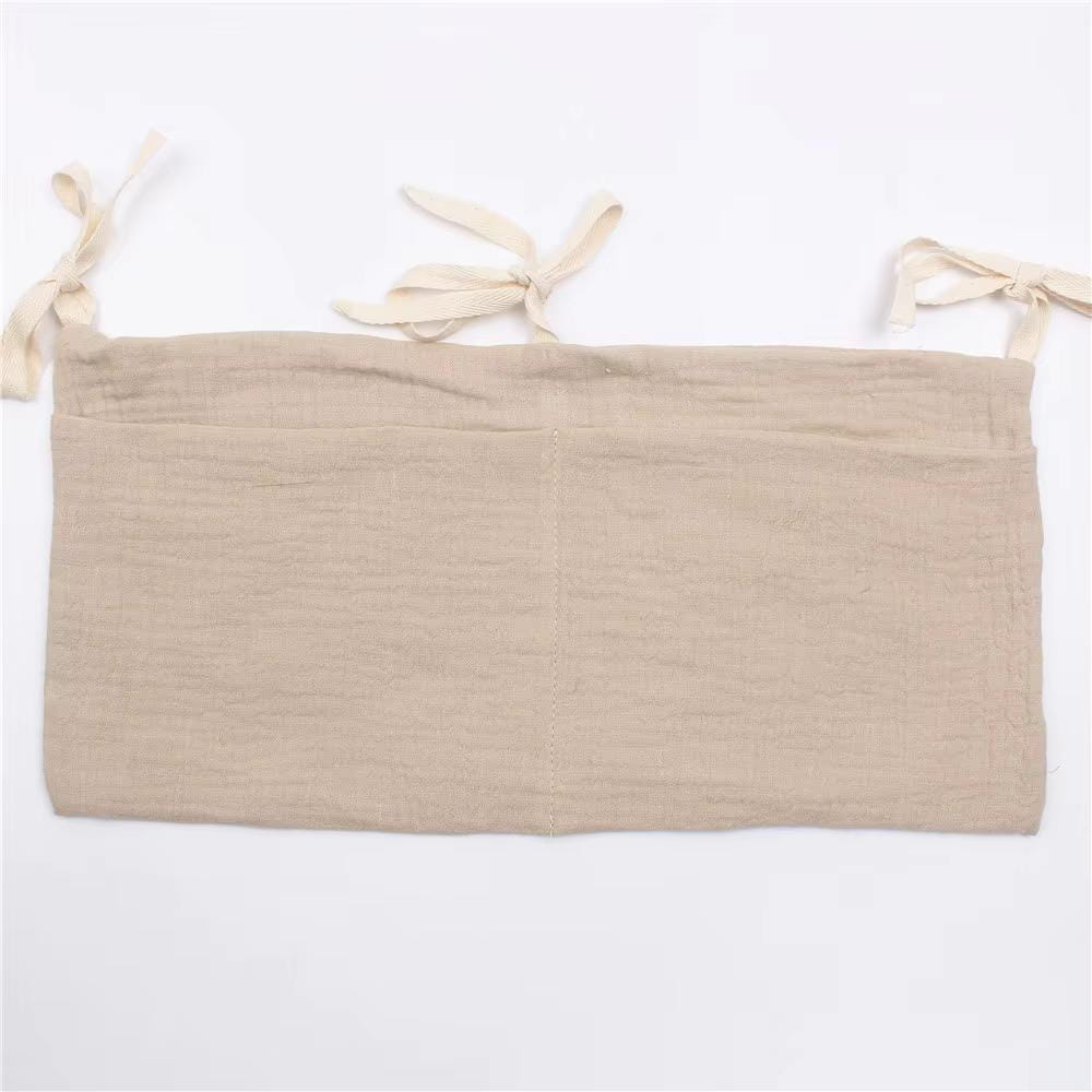 Beige Leinenstoff-Wickeltisch-Aufbewahrungstasche für die Windelorganisation mit drei gebundenen Schleifenbändern oben.