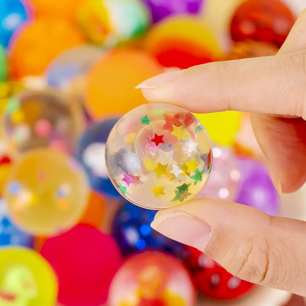 Una bola antiestrés transparente y clara, rellena con confeti de estrellas con forma de estrellas de colores, del surtido de recuerdos de fiestas de bolas a granel elásticas.