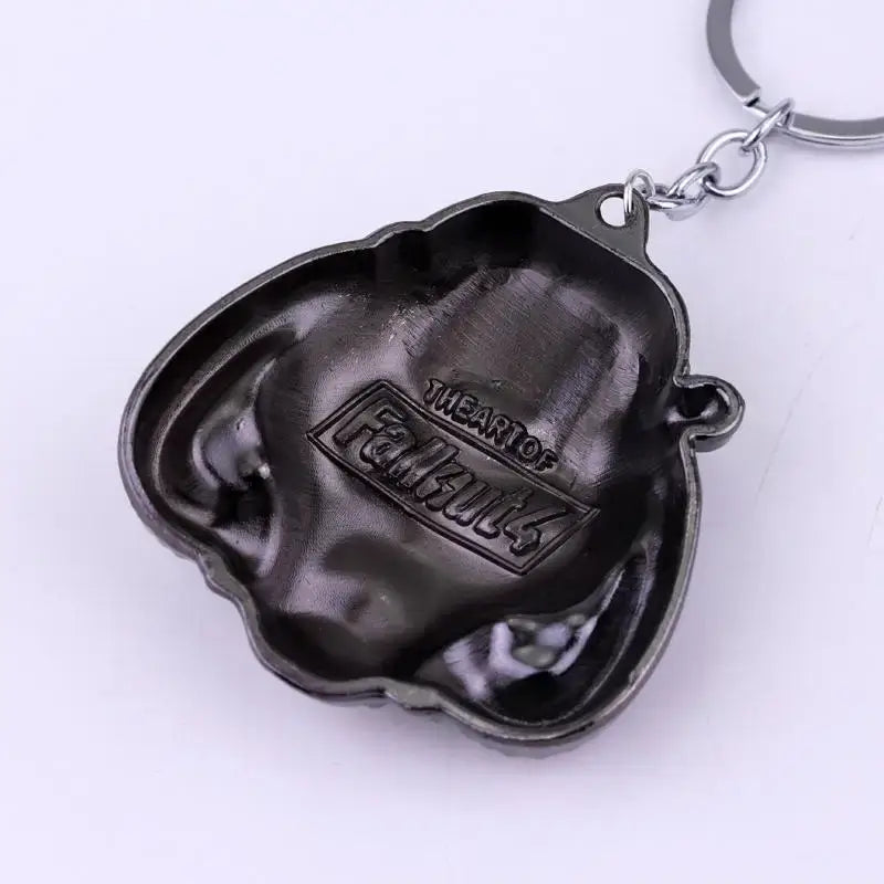 Black metallic Fallout power armor helmet keychain showing the back side with the art of Fallout engraved.