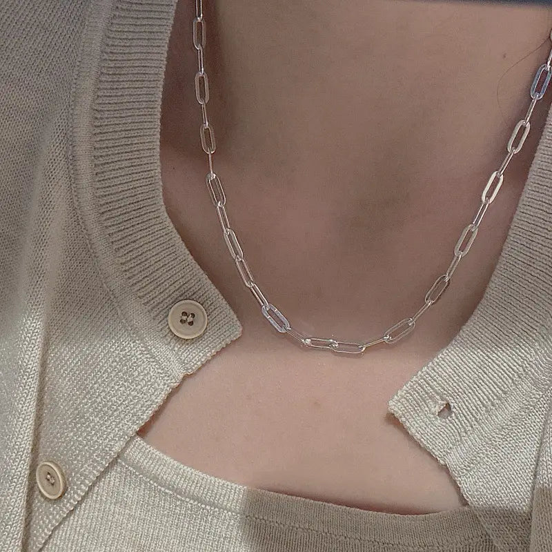 Un collar minimalista de cadena tipo eslabones de papel en plata de ley, con un delicado diseño de eslabones de plata, que se lleva con elegancia alrededor del cuello.