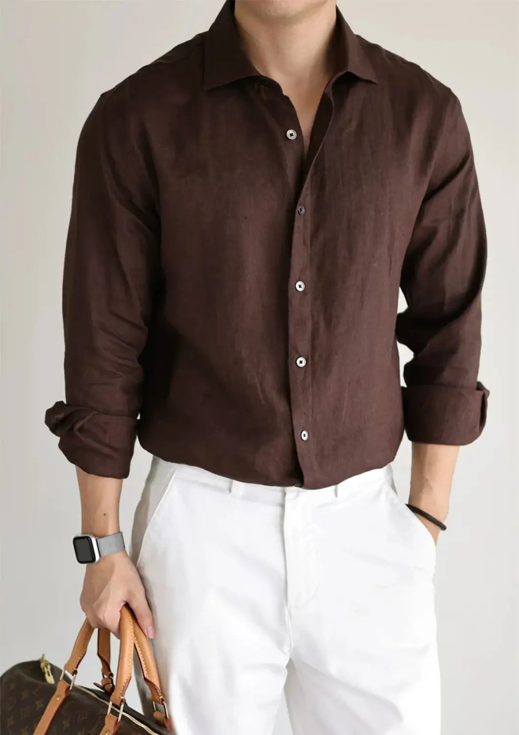 A dark brown cotton linen casual button down shirt with rolled-up sleeves and white buttons.