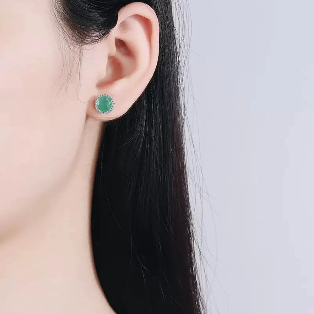 A delicate stud earring featuring a round vibrant green jade stone set in a sparkling silver-toned metal frame from the emerald sterling silver jewelry set.