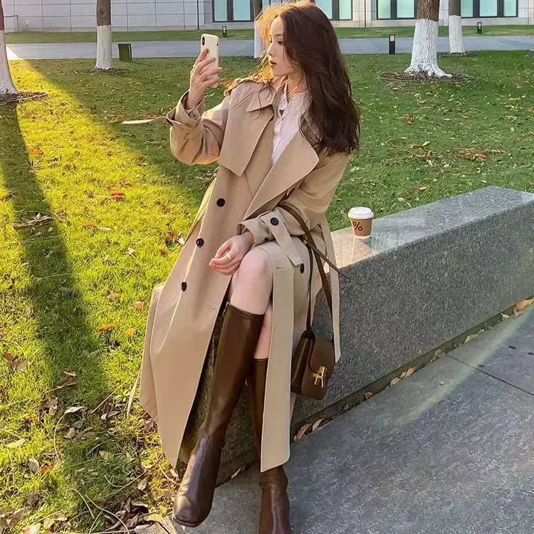 Beige women double-breasted trench coat with black buttons and a belted waist designed as a casual windbreaker.