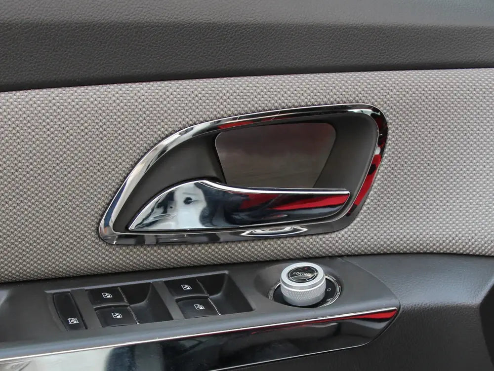 Moldura de la manija de la puerta con acabado en cromo y diseño curvo y elegante, integrada en un panel de tela gris texturizada para el interior de Chevrolet Cruze 2009-2014.