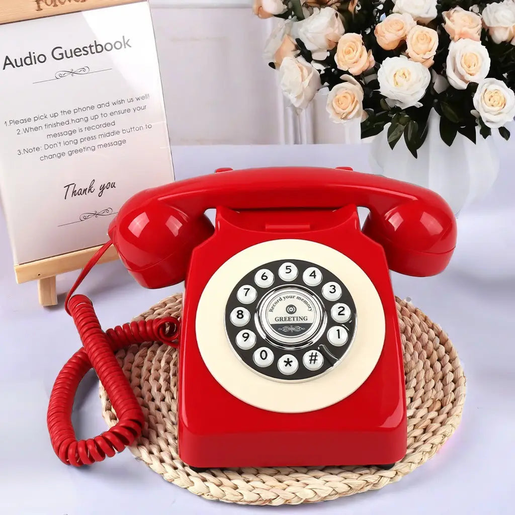 Teléfono de registro de audio antiguo para bodas y eventos con un teléfono rotatorio rojo vibrante con un dial circular color crema y botones negros con números, con acabado de plástico brillante.