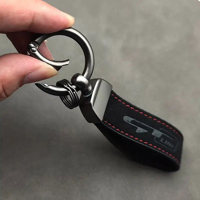 Schwarzer Lederschlüsselanhänger der GT Line aus Wildleder mit roter Steppnaht, metallischem Logo sowie einem robusten Metallring und einer Klammer.