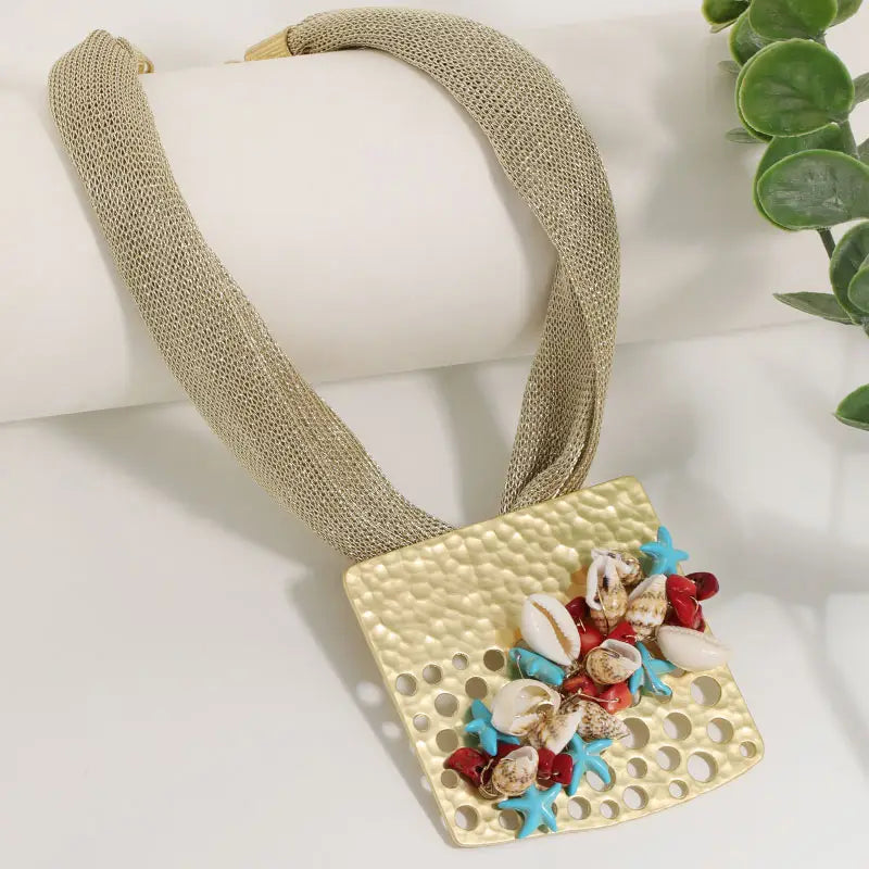 Collier ras du cou géométrique pour femmes, doté d’un pendentif en métal martelé à finition dorée avec un cordon en mesh texturé et des coquillages décoratifs, des étoiles de mer et des touches de corail.