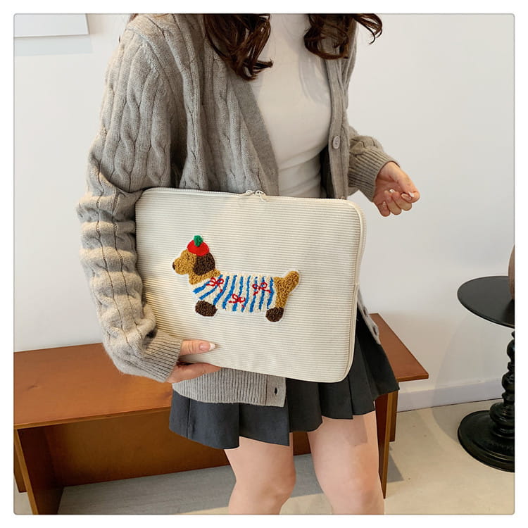 Elfenbeinfarbene Kord-Laptophülle für MacBook Pro mit einem farbenfrohen bestickten Dackel, der ein gestreiftes Hemd und eine rote Mütze trägt.