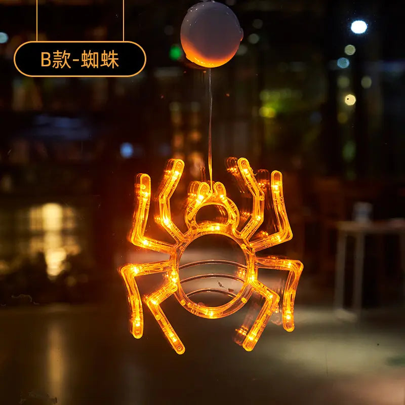 Orange LED spider window decoration with glowing lights and suction cup attachment for Halloween window light battery operated pumpkin ghost decor.