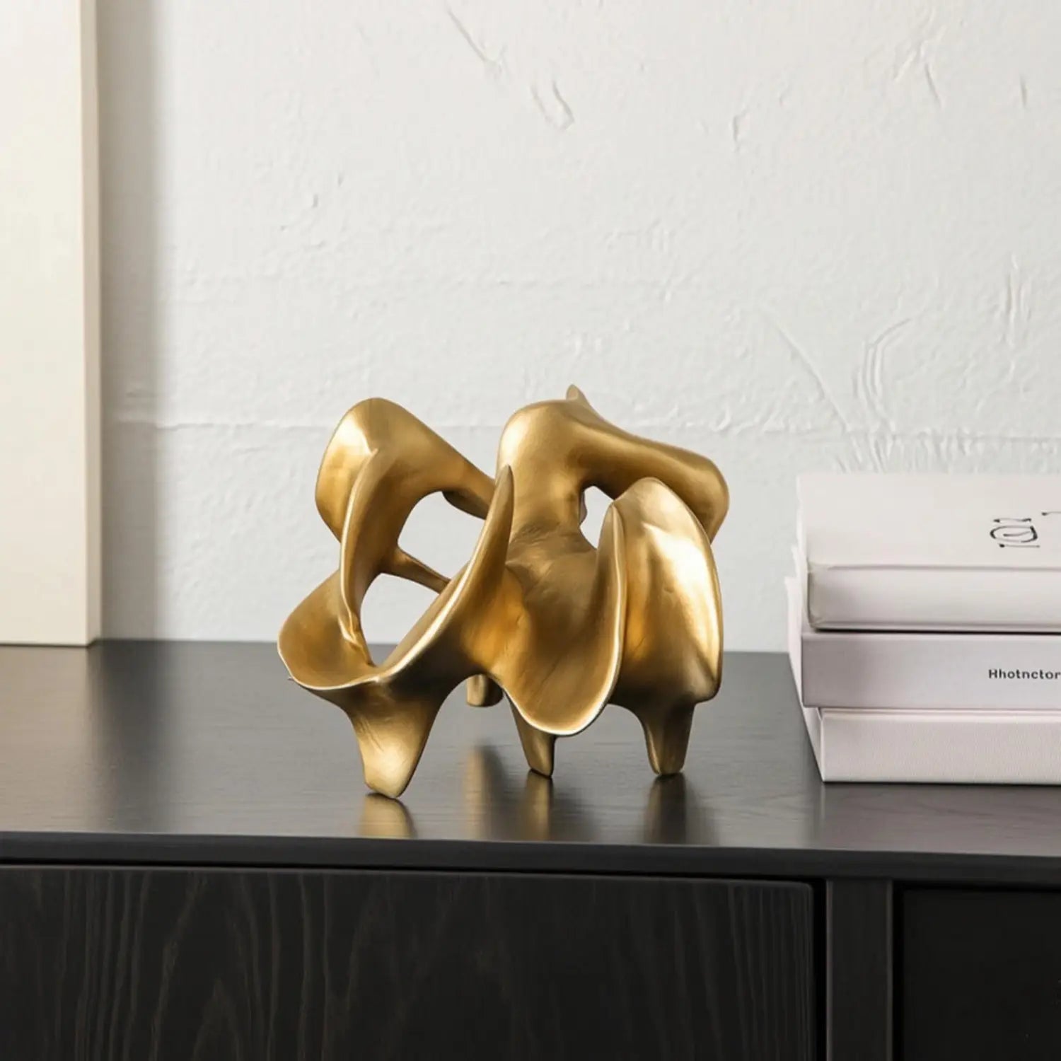 resin decorative item featuring a golden abstract sculpture with flowing intertwined forms and a polished metallic finish