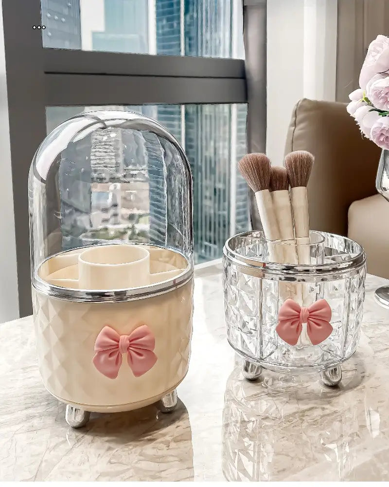 Boîte de rangement tournante pour maquillage et organisation des cosmétiques en verre beige et transparent, avec des accents de nœud rose pour le rangement des cosmétiques.