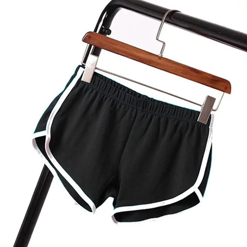 black sports shorts women with white trim and elastic waist hanging on a wooden hanger for casual athletic wear