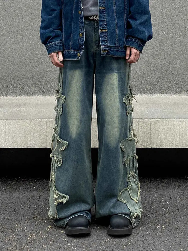 Jeans en denim délavé et déchiré baggy style y2k bleus, avec une coupe très ample (wide-leg) et des détails de patchwork effilochés le long des coutures externes.