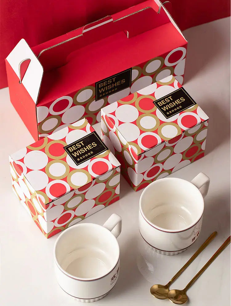 Tasses en céramique blanches avec des accents de bordure dorée et des motifs imprimés subtils, dans un coffret cadeau de deux tasses de couple en céramique pour mariage chinois.