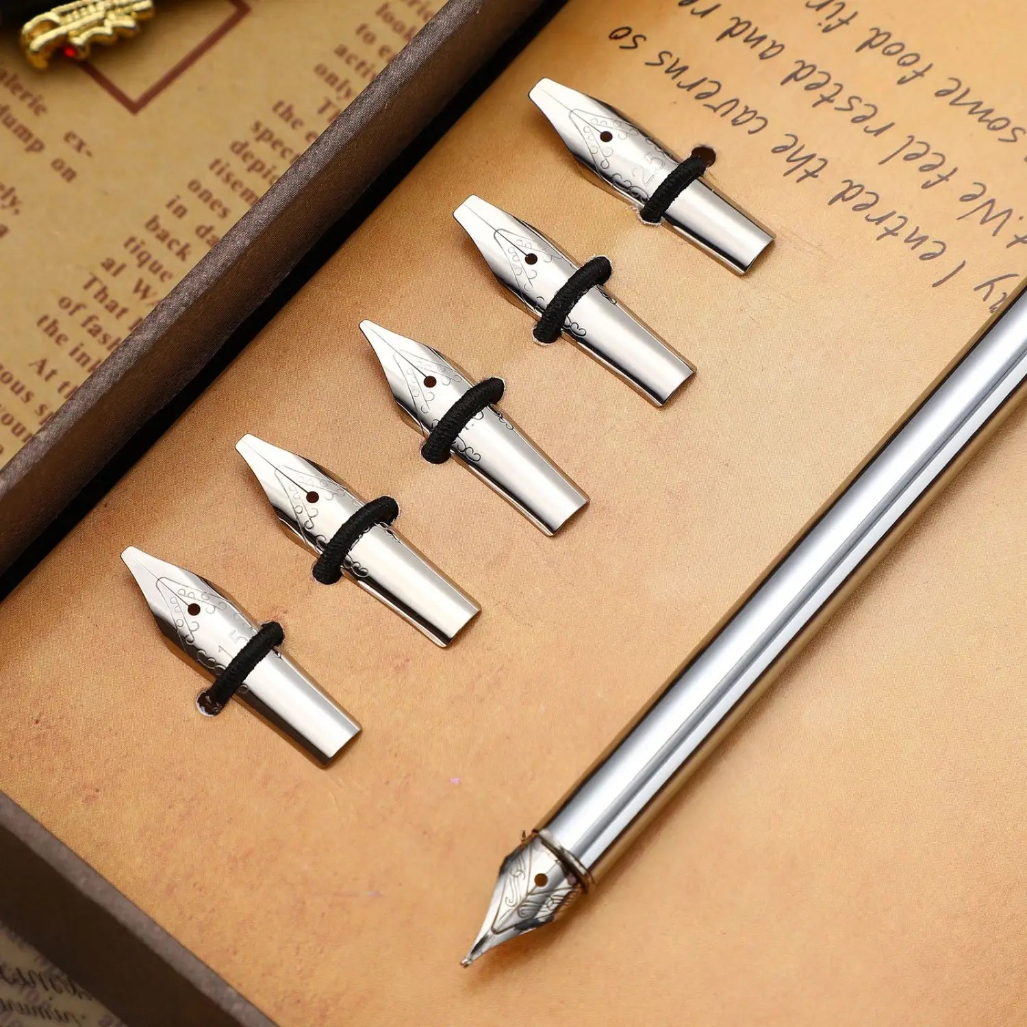 Set of five stainless steel silver fountain pen nibs with black rubber bands and one matching silver stainless steel fountain pen displayed in a wooden box.