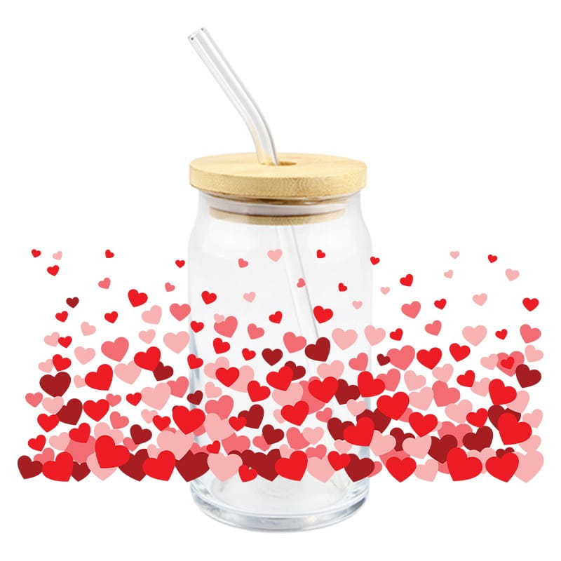 Étiquette autocollante d’enveloppement pour gobelet UV DTF de la Saint-Valentin, sur un verre à boire en verre transparent avec couvercle en bambou et paille transparente, entouré de cœurs rouges et roses flottants.