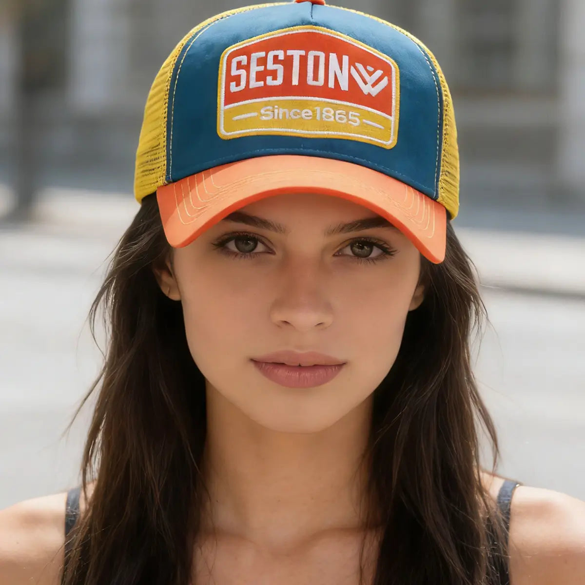 A vibrant blue and yellow trucker hat with an orange brim featuring a red patch with seston logo and since 1865 lettering in white.
