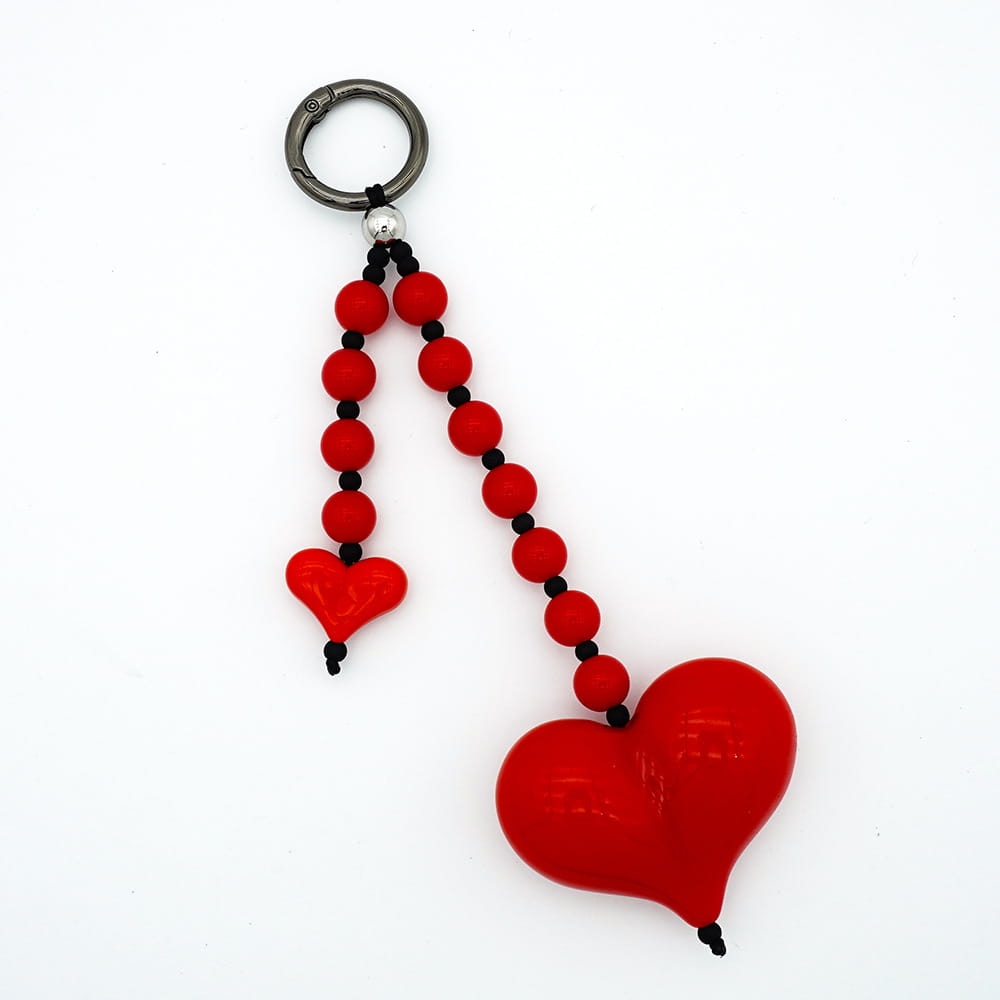 Pendentif pour sac à perles en forme de cœur, comprenant un pendentif en forme de cœur rouge brillant et une chaînette de perles rouges et noires, avec deux petits pendentifs en forme de cœur suspendus.