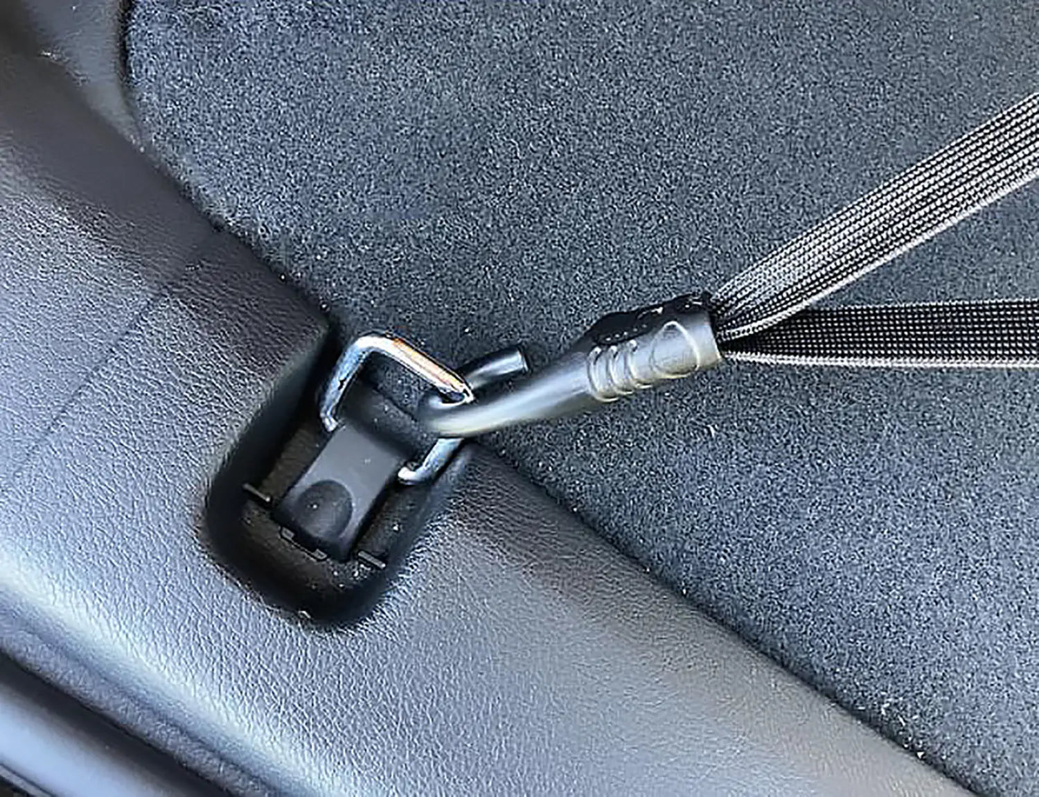 black car seat belt anchor with silver metal hook and textured strap detail of a car trunk organizer elastic cargo strap