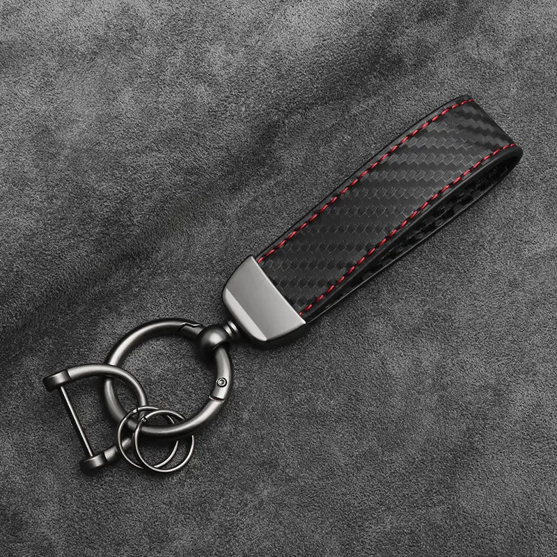 Black carbon fiber car keychain with red stitching and a metallic clasp designed for car keys.