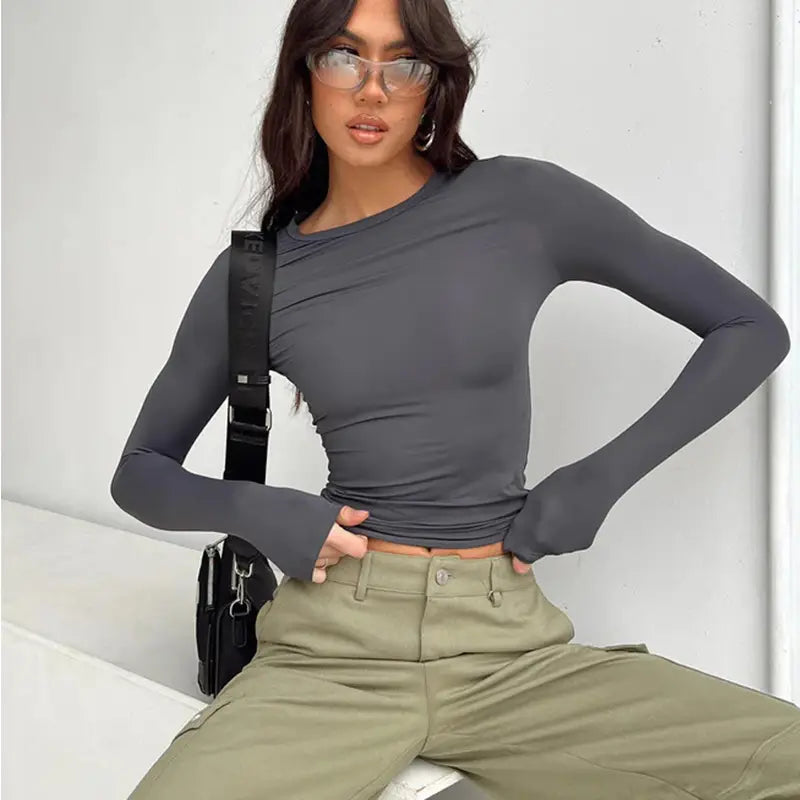 Blusa corta ajustada tipo slim fit para mujer en gris oscuro con diseño elegante, con cuello asimétrico y acabado fruncido.