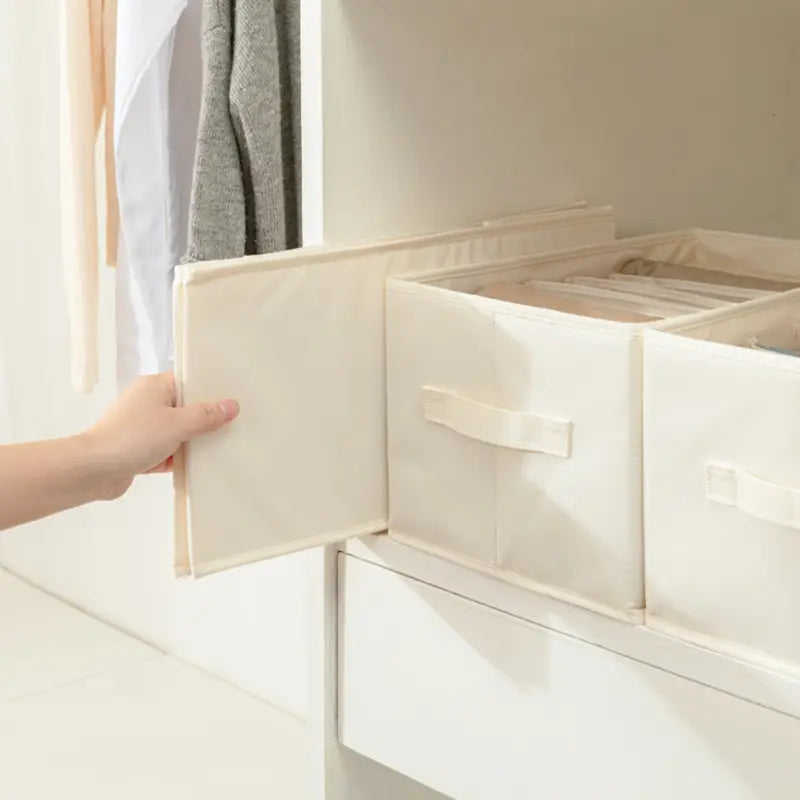 off-weiße Stoff-Wäscheaufbewahrungsbox mit weicher, strukturierter Oberfläche und verstärkten Griffen, ausgelegt für die Aufbewahrung im Kleiderschrank und für Jeans.